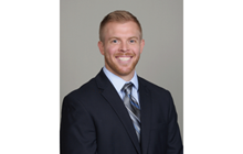 Garrett Gilbert smiles in a black suite in front of a gray background. 